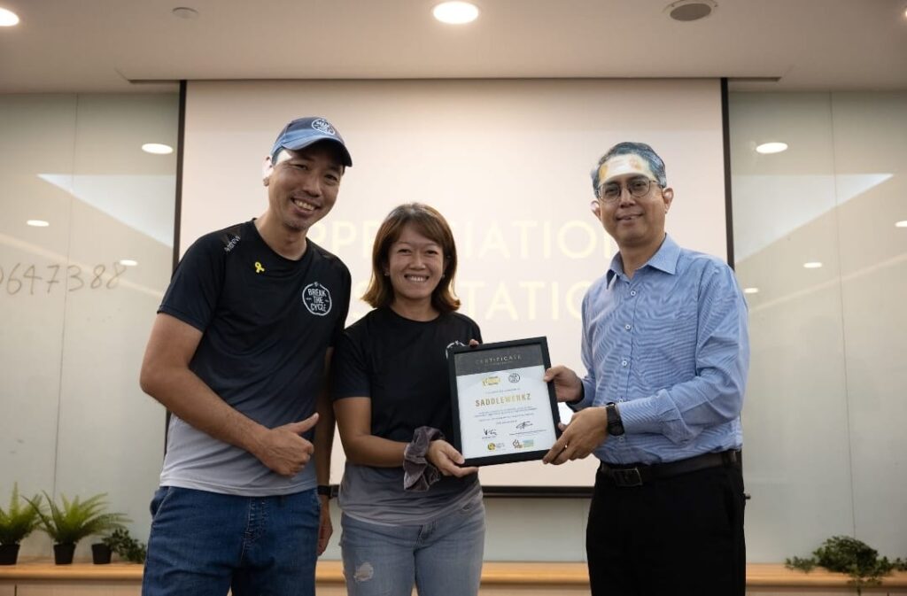Two Saddlewerkz coaches on stage receiving a framed certificate of appreciation