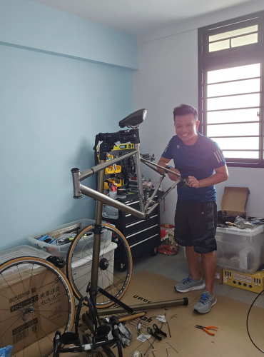 Coach Joseph in a home bike workshop with a bicycle frame on a repair stand